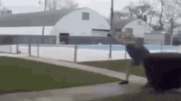 a person is walking down a sidewalk next to a pool .