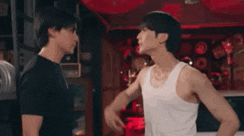 two men are standing next to each other and one is flexing his muscles .