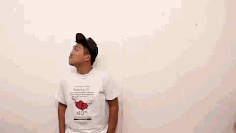 a man in a white t-shirt with a heart on it is standing next to another man .