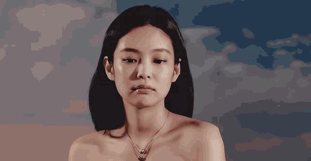 a woman without a shirt is wearing a gold necklace