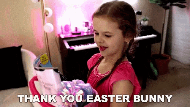 a little girl in a pink shirt is holding a basket of easter bunny