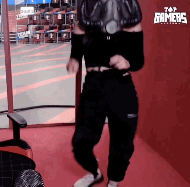 a girl wearing a gas mask is dancing in front of a sign that says top gamers