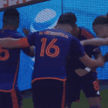 a group of soccer players are celebrating a goal in front of a sign that says energy