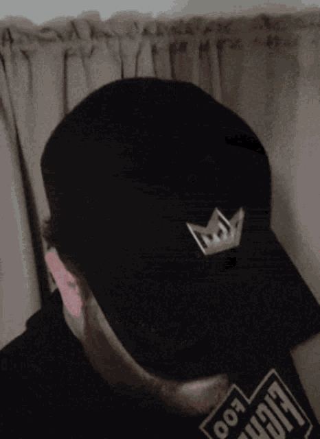 a man wearing a black hat with a crown on it and a shirt that says foo