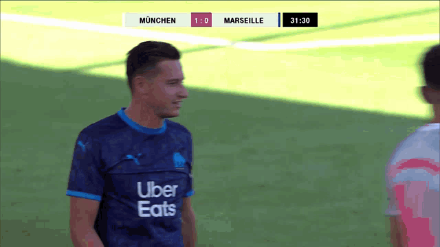 a soccer player wearing an uber eats jersey stands on a field