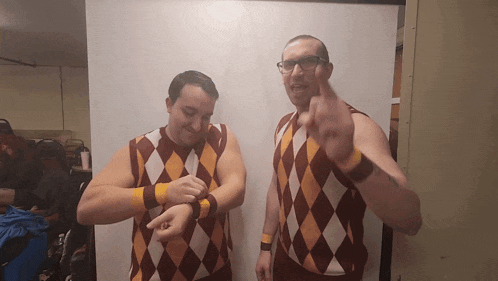 two men wearing argyle sweaters and wristbands are pointing at their wrists