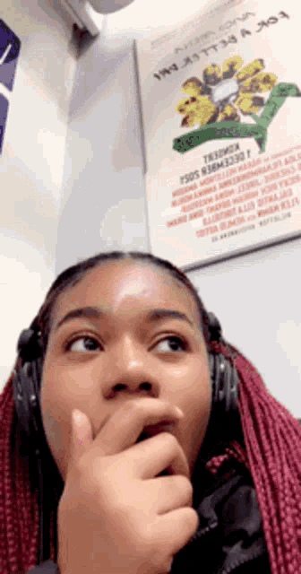 a woman wearing headphones looks surprised in front of a sign that says " ysds r38m330t "