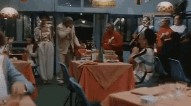 a group of people are gathered around tables in a restaurant