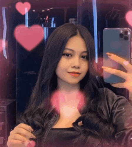 a woman is taking a selfie in front of a mirror with hearts in the background