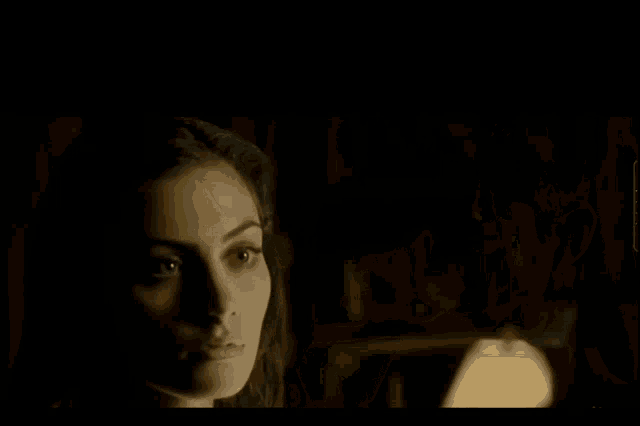 a man and a woman are looking at each other in a dark room in a movie .