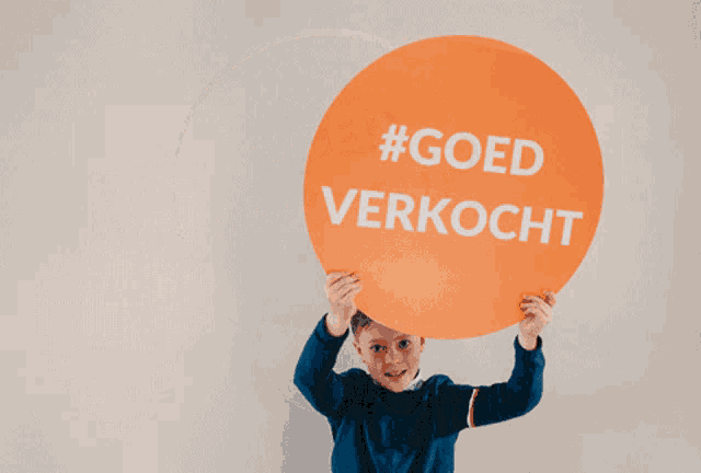 a boy holds up a sign that says #goed verkocht