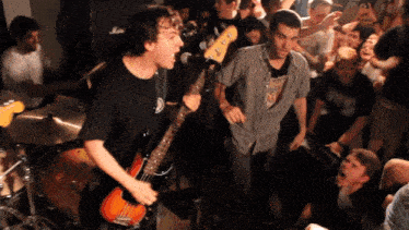 a man singing into a microphone while playing a guitar in front of a crowd