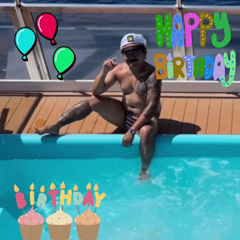 a man in a bathing suit sits in a pool with birthday candles and balloons around him