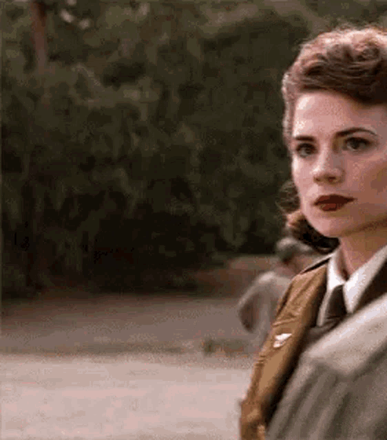 a woman in a military uniform and tie is standing next to a man .