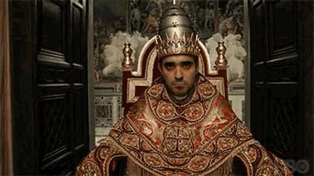 a man is sitting on a throne wearing a crown and robe .