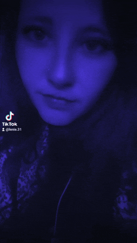a close up of a woman 's face with a blue background and a tiktok logo on the bottom