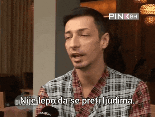 a man in a plaid shirt is talking into a microphone with the words nije lepo da se preti ljudima above him