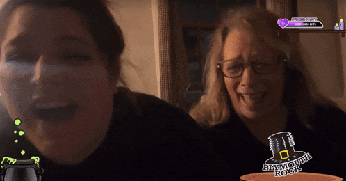 two women laughing in front of a plymouth rock logo