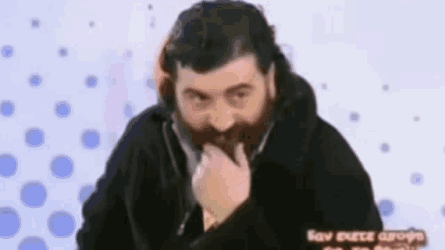 a man with a beard and a black jacket is eating something .