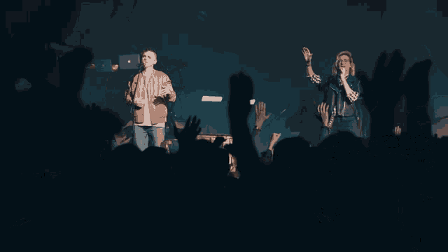 a woman singing into a microphone in front of a crowd at a concert