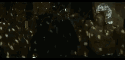 a person in a white coat is standing in a dark room with their arms outstretched .