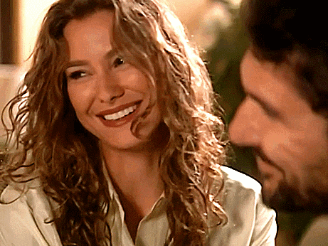 a woman with curly hair is smiling at a man with a beard