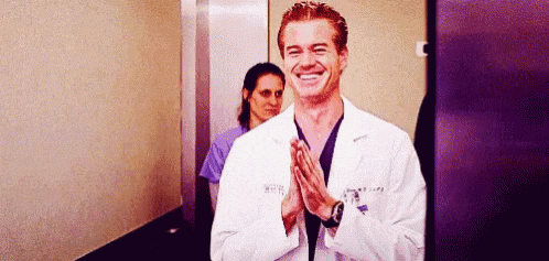 a man in a lab coat is applauding in a hallway .