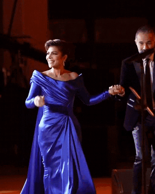 a woman in a blue dress is dancing on stage