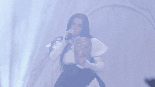 a woman singing into a microphone and holding a donut