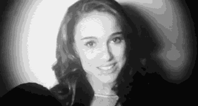a black and white photo of a woman smiling in a dark room .