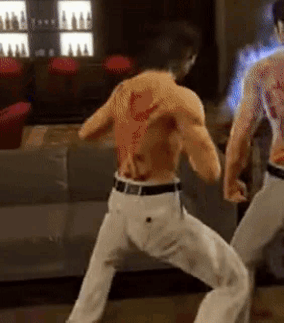 a shirtless man with a tattoo on his back is standing next to another shirtless man