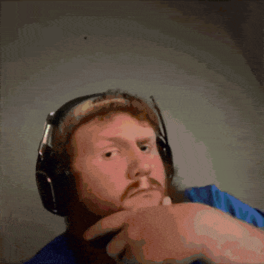 a man with a beard is wearing headphones and making a funny face