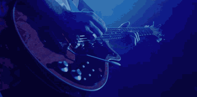 a person is playing a guitar in a dark blue background