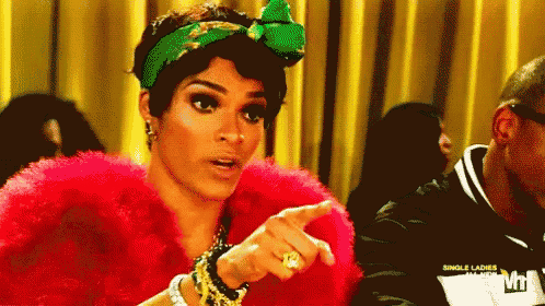a woman wearing a red fur coat and a green headband is pointing at something