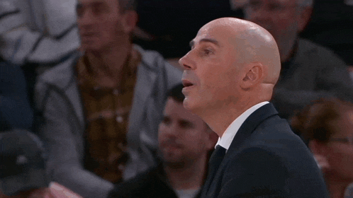 a bald man in a suit and tie is clapping