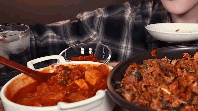 a person is sitting at a table with a bowl of food and a plate of food