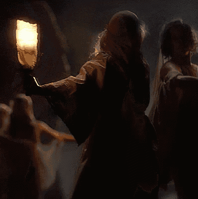 a couple dancing in a dark room with a light behind them