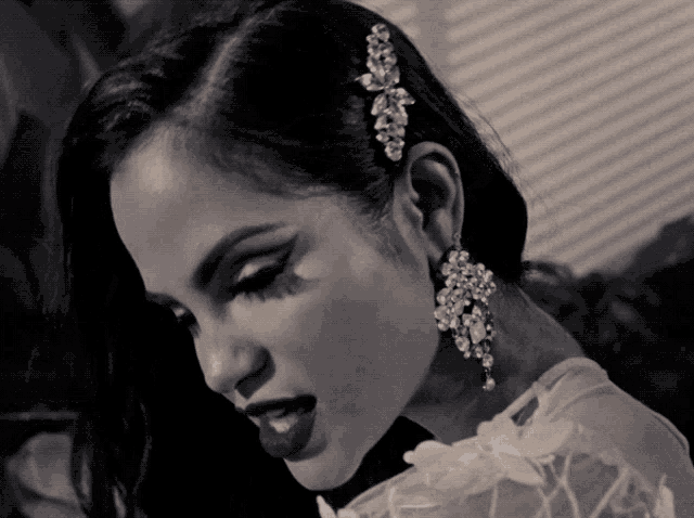 a woman wearing a white dress and earrings looks down