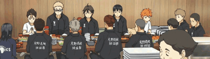 a group of people are sitting around a table and one of their jackets says ics on the back