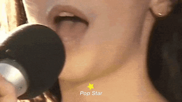 a close up of a woman singing into a microphone with the word pop star on the bottom right