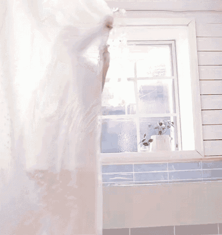 a woman is wrapped in a white towel and smiling in front of a window