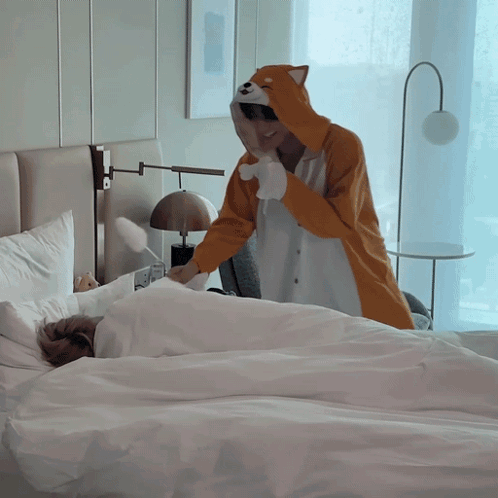 a person in a fox costume is standing over a bed