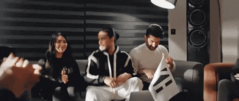 a group of people are sitting on a couch and one of them is holding a piece of paper that says ' a '