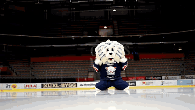 a mascot is kneeling on the ice in front of a sign that says jule