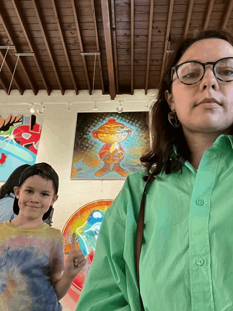 a woman wearing glasses and a green shirt is standing next to a boy