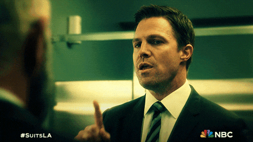 a man in a suit and tie is talking to another man with a nbc logo behind him