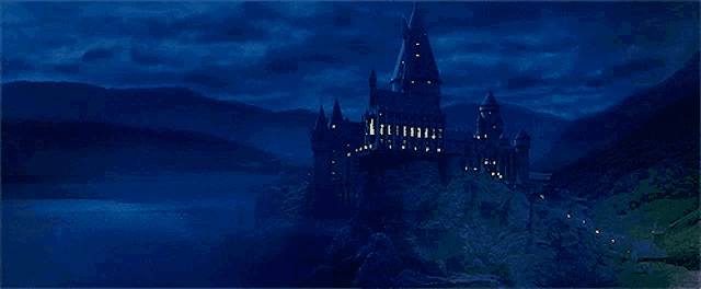 a large castle sits on top of a hill at night