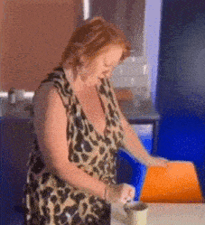 a woman in a leopard print dress sits at a table with a cup