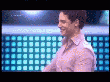 a man in a pink shirt is smiling in front of a wall that says circus on it