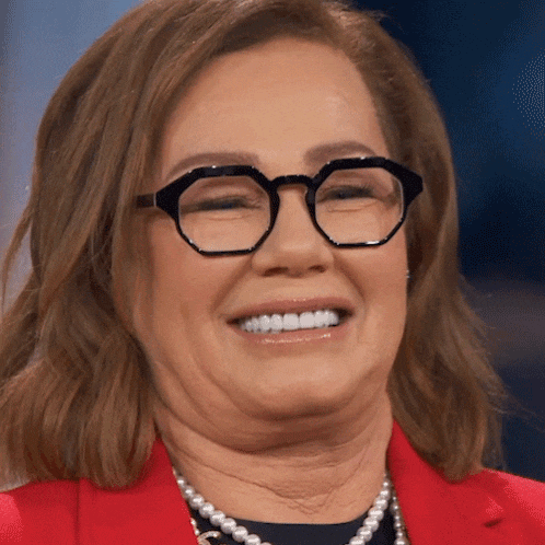 a woman wearing glasses and a red jacket smiles for the camera